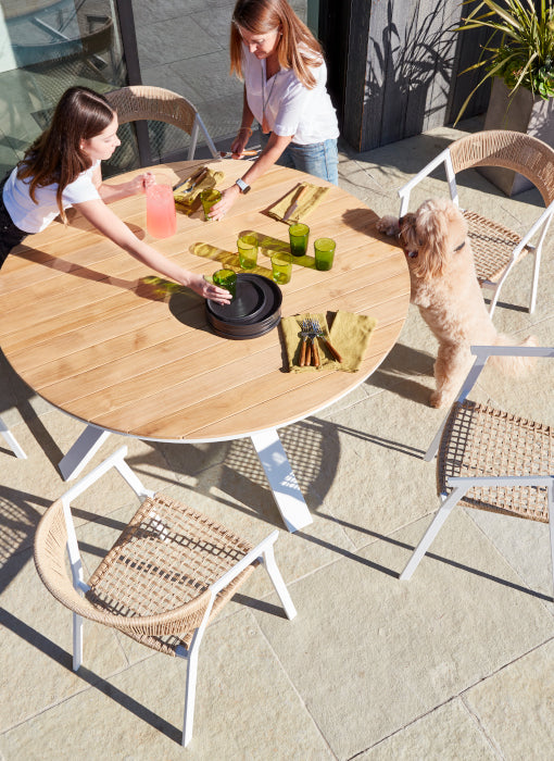 A mother and daughter set the Portola dining table in white aluminum
