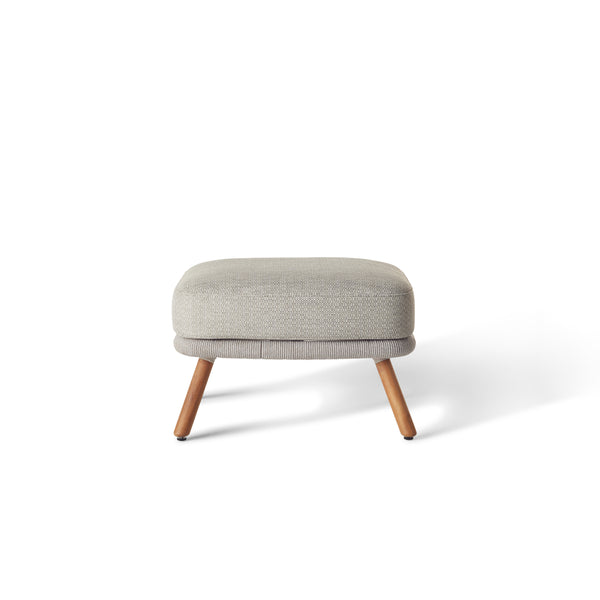 Avila Ottoman by Terra Outdoor Living — features a minimalist teak and aluminum frame with rounded edges and a thick, weather-friendly cushion, designed to function as a footrest or extra seating with compact proportions and a refined coastal look. Stands on premium teak legs.