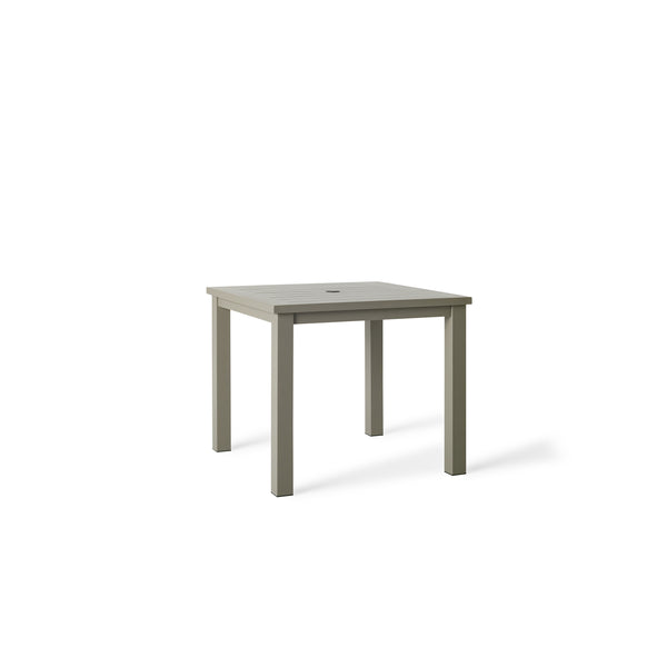 Belvedere Square Dining Table by Terra Outdoor Living in Quartz Grey, a warm grey tone, shown with a slatted aluminum top and central umbrella hole, featuring a clean-lined, modern silhouette in a compact size for versatile outdoor placement. 