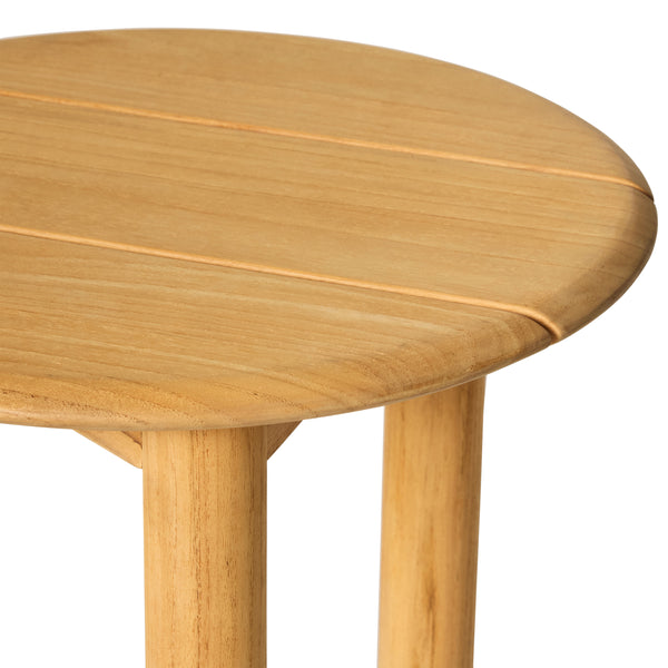 Close up of Stinson Side Table by Terra Outdoor Living. Made of premium teak in a natural finish, with curved edges. Compact slatted top provides space for a drink or book and allows water to drain, perfect alongside outdoor seating.